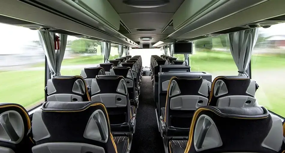 Tomma platser i en modern, ren buss med stora fönster och takförråd.