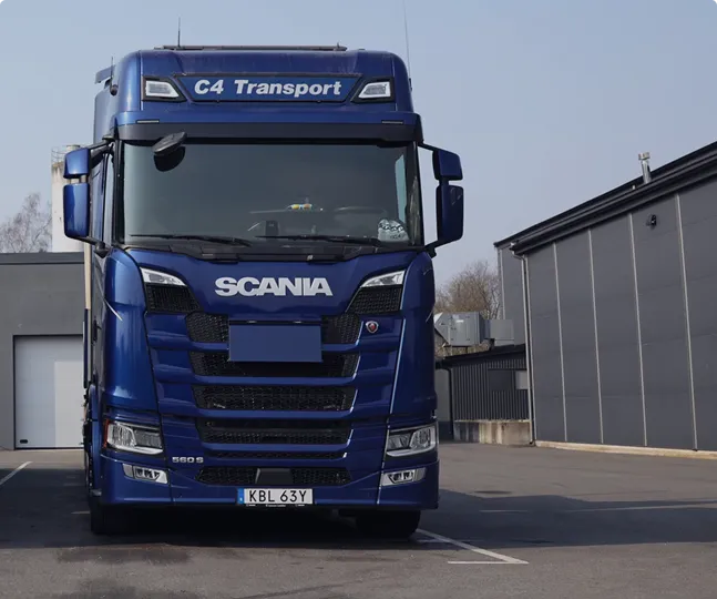 En blå Scania lastbil märkt C4 Transport står parkerad på ett industriområde.